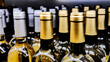 Close-up of many silver and golden wine bottles on a store shelf 