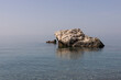 Weathered Rock in Serene Sea. Clear blue waters of the Mediterranean Sea, under a soft sky.