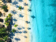Aerial view of empty sandy beach, shadows of palms, blue sea with waves at sunset. Summer vacation in Zanzibar. Top drone view of green palms, ocean with azure water. Tropical background. Travel