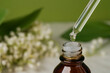 Cosmetic oil in a bottle of drip, on a light background. Lily of the Valley Essential Oil. Side view. Space for text.     