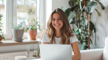 Portrait of a young happy female freelancer sitting in the kitchen and working on project, watching movie on laptop, studying, blogging, resting and chatting online. Distant education, work