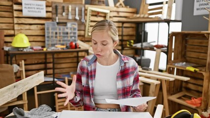 Canvas Print - Frustrated blonde carpenter, young woman in rage, screaming and shouting furiously while sitting at carpentry table in studio workshop, full of anger and stress.