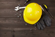 Happy labor day concept. Construction tools, yellow helmet on dark wooden background, copy space.