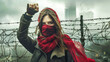 A woman wearing a red scarf raises her hand in protest behind barbed wire, showcasing her resilience and determination