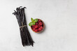 Vanilla beans with raspberries on gray background
