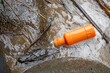 selective focus orange chemical bottle in the river Throwing the garbage without considering nature A bottle of insecticide, the garbage of a careless farmer. There is space for text.