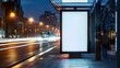 At night, a blank white vertical digital billboard poster at a city street bus stop sign, serving as a street advertising mockup for a bus stop.