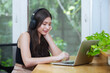 Asian female wear headphone using laptop conference, typing message or watch movies and listen to music. women freelancer working at home. Online meeting via video conference. chat communication.