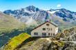 Nestled in the Italian Alps, the Tabaretta Hut offers a panoramic view of mountains around Ortles, basking under a clear blue sky on a bright sunny day.