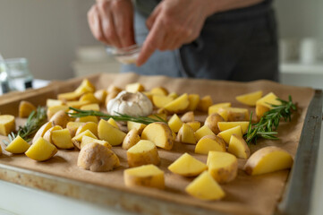 Wall Mural - Woman preparing fresh cubed potatoes on a baking sheet for making roasted potatoes