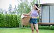 Bath in the warmth of the sun, a young woman stands in green grass backyard. Dressed in a purple top paired with classic denim shorts hanging cloths, Minimal lifestyle laundry eco energy concept