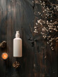 An unlabeled cosmetic bottle lies on a dark textured wooden table. Next to nice decoration.