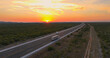 AERIAL: Orange sunrise sunbeams illuminate truck driving across rural Croatia.
