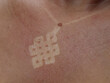 CLOSE UP, DOF: Unhealthy red burnt skin with visible white necklace pendant mark. Young lady was overdoing her tanning under the strong summer sun and suffered severe and harmful burns on her skin.