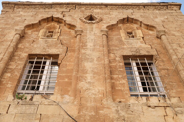 Two windows on the facade of a traditional house in the old town of Mardin, decorated with elaborate carved patterns and details, Mardin, Turkey