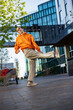 Vertical Screen: Young Female Hip Hop Dancer Freestyling On City Street Among Buildings. Street Style Performer Doing Improvisation In Urban Environment. Caucasian Woman Practicing Choreography.