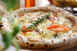 Wood fired pizza with cheese, smoked salmon, onion, rosemary, on a wooden cutting board, selective focus, close up.