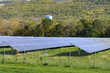 Solar power plant with rows of solar panels in a forested mountain landscape in autumn