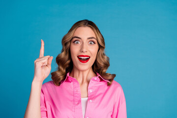 Poster - Photo portrait of lovely young lady point up empty space dressed stylish pink garment hairdo isolated on blue color background