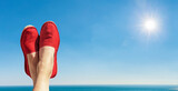 Fototapeta Dmuchawce - Damenbeine mit Roten Stoffschuhen vor blauem Himmel