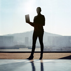 Leinwandbilder - Silhouette, woman and laptop by urban office window for networking, email and development. Website creation, technology and project research for start up company in workplace for small business