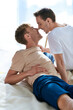 © Bliss - Two men in casual clothes lying together on a comfortable bed.