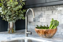 Kitchen Sink With Metal Faucet On Marble Countertop, Side View. Green Asparagus In Wooden Bowl Close To Eucalyptus Branch In Black Vase With White Tile On Background. Healthy And Vegetarian Food