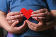 World mother day concept background. Mother and son hands with red shape heart close up.