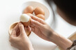 woman holding boil egg and pilling off eggshell