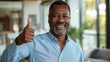 © HelenP - A smiling man in an office setting gives a thumbs up.