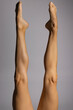 Bare female legs, top view on a gray background.