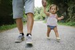 baby girl walking together with her grandfather during a stroll in a park. Concept of grandpa and nephew growing