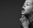 boy praying to God with hands together on grey black background with people stock image stock photo	