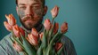 A portrait blending masculinity and softness, featuring a tattooed man in a pinstripe shirt holding a bouquet of delicate pink tulips against a matching pastel background