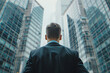 © mediahain.de - Businessman in suit looking over shoulder at towering glass skyscrapers, concept of corporate success and ambition