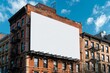 A clear blue sky backdrop accentuates a blank vertical billboard on a brownstone building, poised for a striking ad