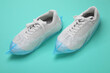 Sneakers in shoe covers on turquoise background, closeup