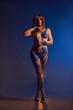 Sensual naked woman with body art standing in dark studio