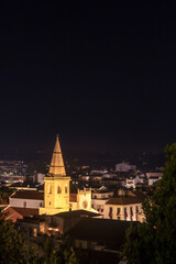 Sticker - Night landscape of the city of Tomar in Portugal with the tower of the main church illuminated against a dark background.