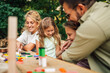 © Zamrznuti tonovi - Cheerful family tickling and hugging in nature at picnic table.