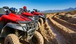 A row of red ATV quads parked along the muddy course in the desert