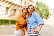 Two young women  in trendy summer clothes posing on the street background. Summer playful mood concept. Concept of lifestyle, fashion, travel.