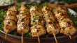   A tight shot of chicken skewers on skewers against a platter backdrop, surrounded by various food items in the distance