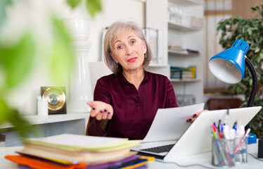 Wall Mural - Portrait of positive mature woman at workplace in office