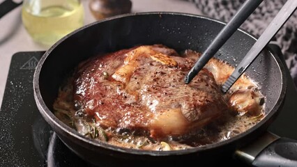 Poster - A chef cooks a beef steak on a pan in the kitchen and turns it to the other side, close-up. Process of making delicious steak.