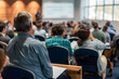 © Prasanth - Business and entrepreneurship symposium. Speaker giving a talk at business meeting. Audience in conference hall. Rear view of unrecognized participant in audience.