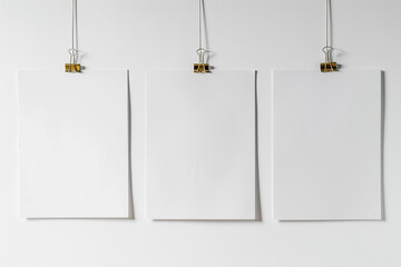 Blank paper frames suspended by clips against a pristine white backdrop -