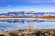 Buffalo Bill Cody Reservoir and snow-covered Carter Mountain Range during spring with ice in the water and blue cloudy sky during spring in Wyoming, USA.  