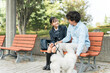 公園のベンチに座る犬の散歩をする愛犬家の親子・娘・父親
