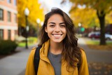 Fototapeta Londyn - A Radiant Young Woman Smiling Confidently as She Stands Before the Bustling Student Apartment Complex on a Bright Autumn Day